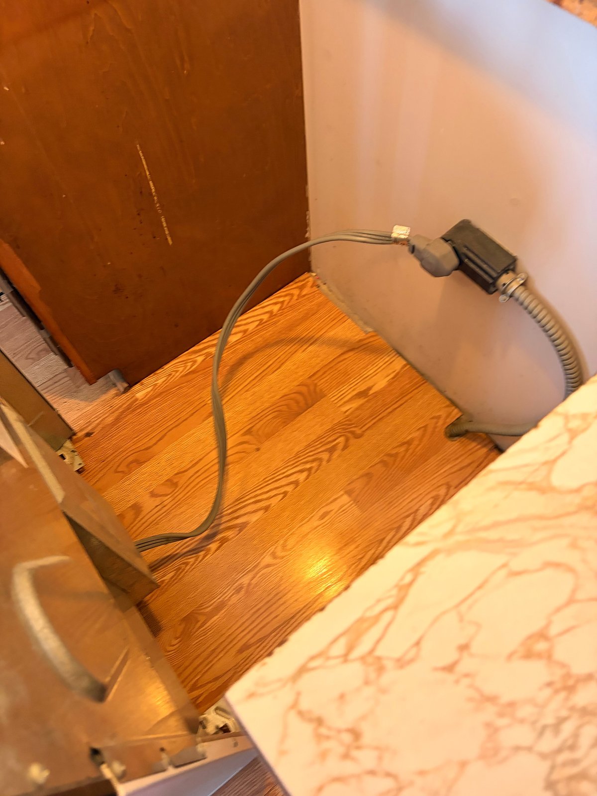 White cylindrical humidifier on wooden floor with power cord connected to wall outlet