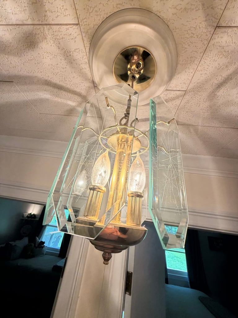 Ceiling light fixture with glass shade and brass bulbs during installation with teal support straps