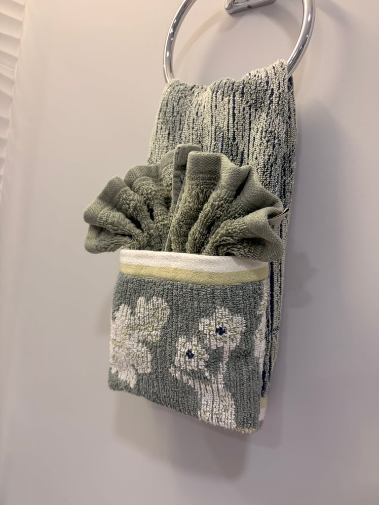 Green and white towels hanging on a chrome ring attached to a bathroom wall