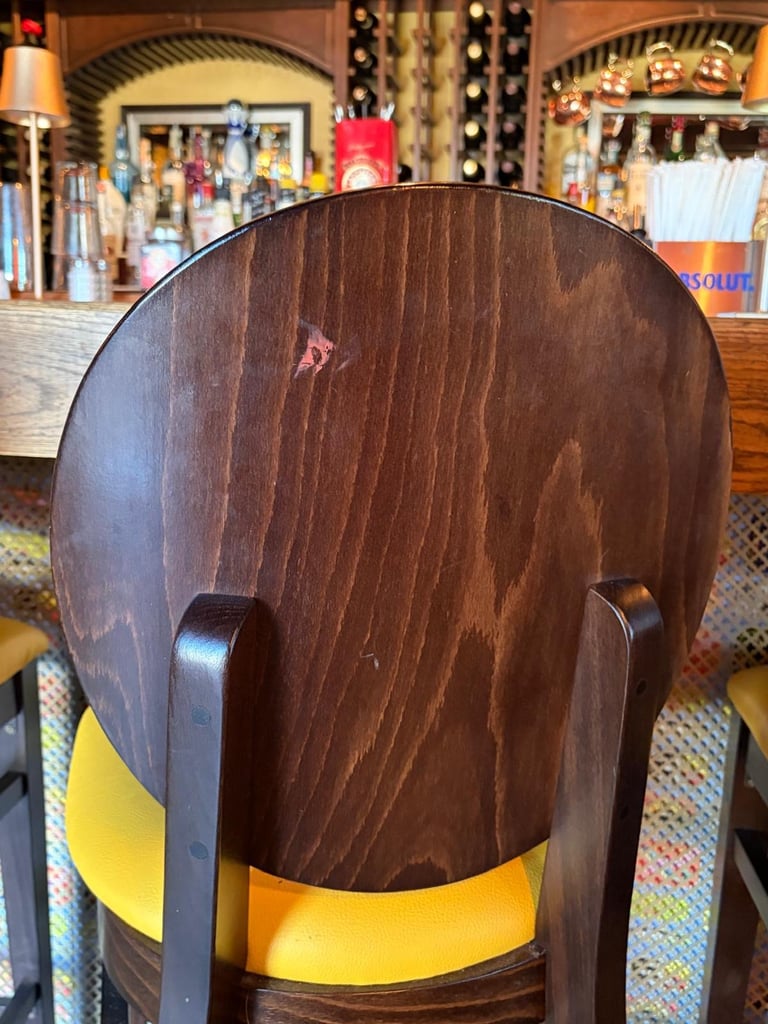 Back view of a wooden chair with yellow seat in a retail clothing store interior