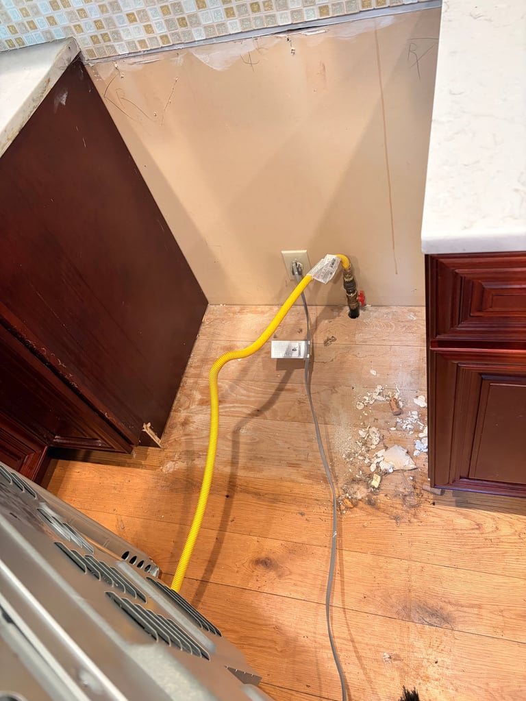 A yellow extension cord runs across a wooden floor in a renovation space with drywall and tile work visible
