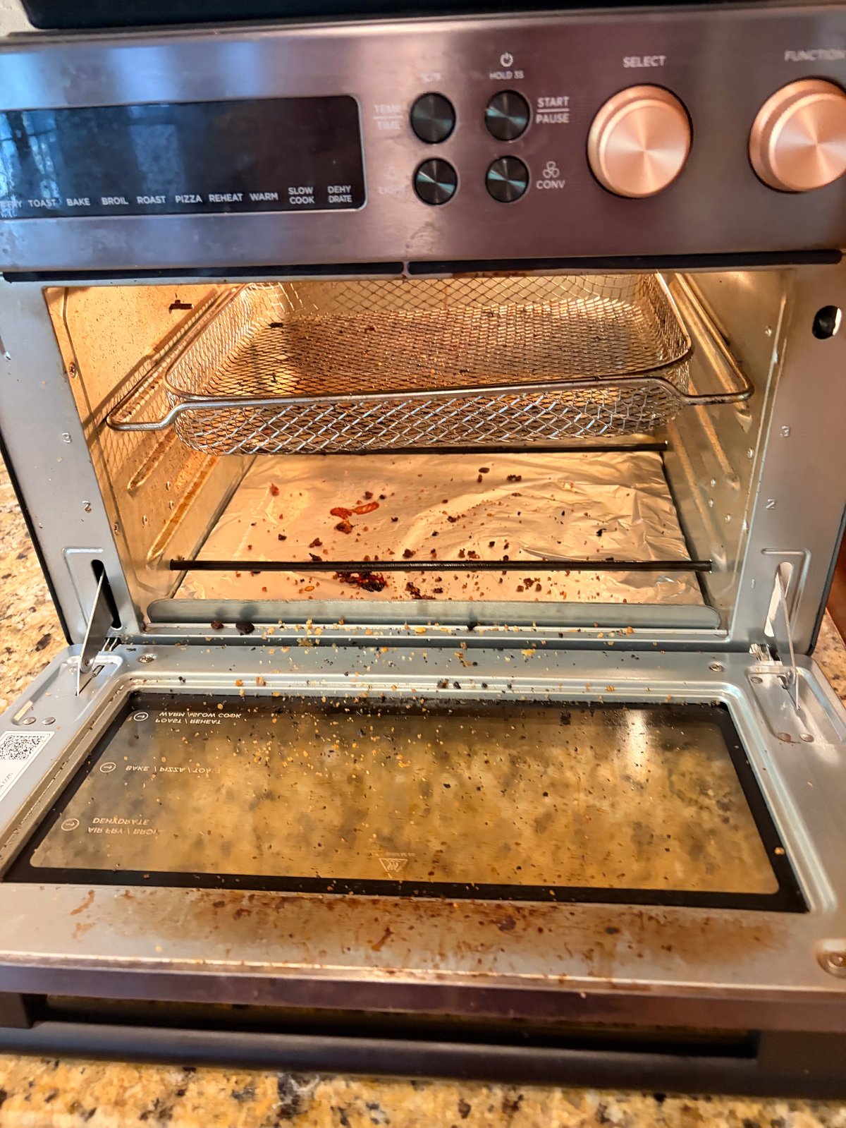 Open oven with baking sheet inside and crumb-covered interior showing signs of spills and heavy use