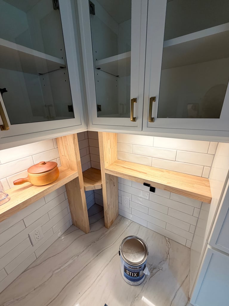 Kitchen under renovation with white subway tile, wooden countertops, glass-front cabinets, and paint can on floor