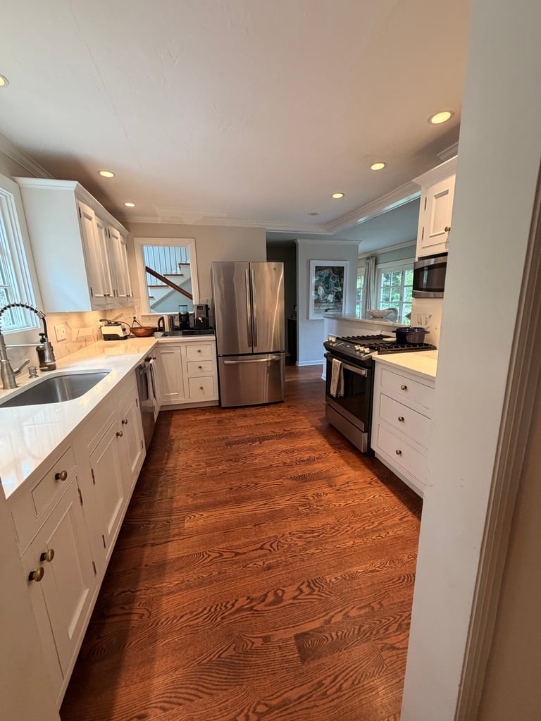 Modern kitchen with white cabinets, stainless steel appliances, hardwood flooring, and recessed lighting