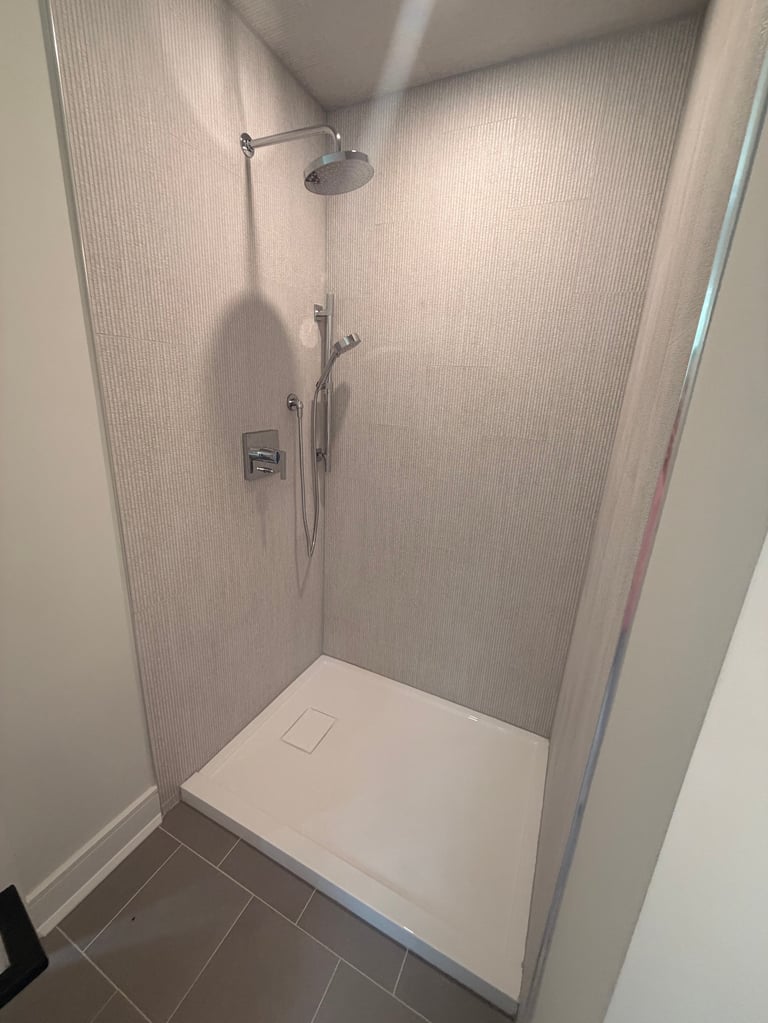 Modern shower enclosure with white tile walls, rainfall showerhead, handheld spray, and white base tray
